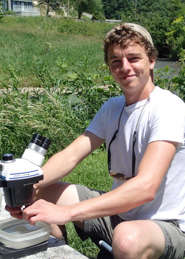 Michael Thomas with microscope on a riverside