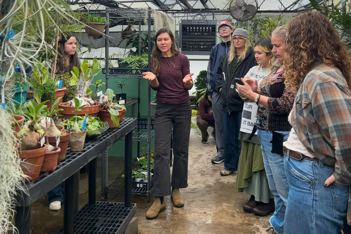 A woman guides a group of people touring the Greenhouse.
